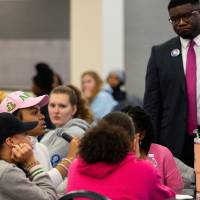 Albert&nbsp;Okwei stands by a table of students at a round table